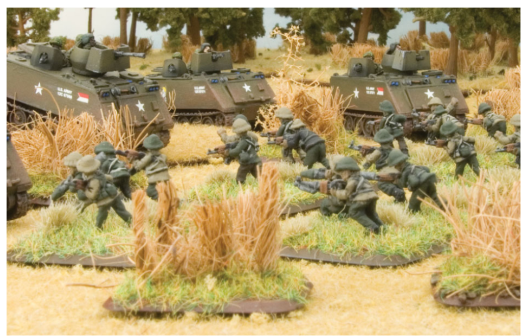 Scale model diorama of WWII US Army tanks and infantry advancing through tall grass field