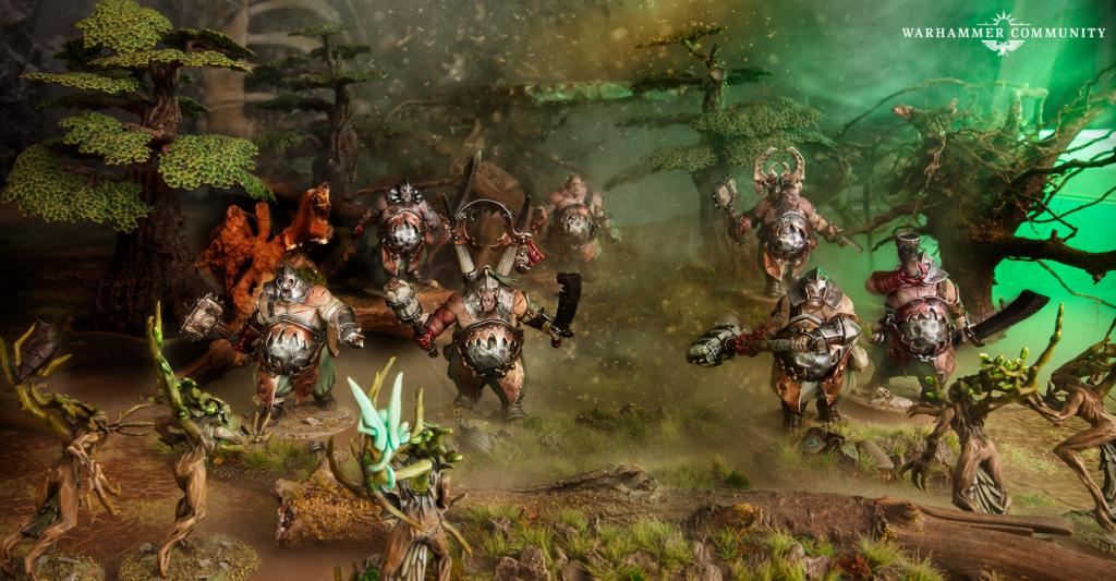image Frontline Gaming Group of armored orc warriors charging through a misty forest battlefield with weapons raised and rocky terrain surrounding them Warhammer Community logo in the corner