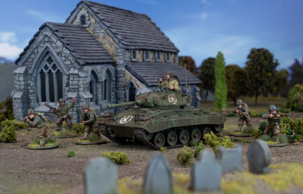 WWII era diorama with a green armored vehicle and troops near a ruined stone church set in a rural battlefield backdrop