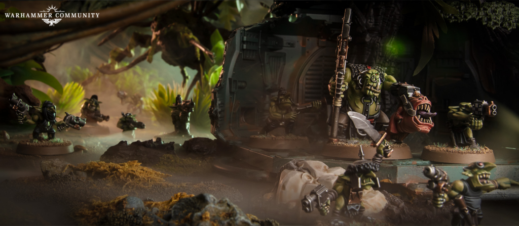 Warhammer Community logo visible in a dense jungle battle diorama with orc warriors attacking a large armored vehicle