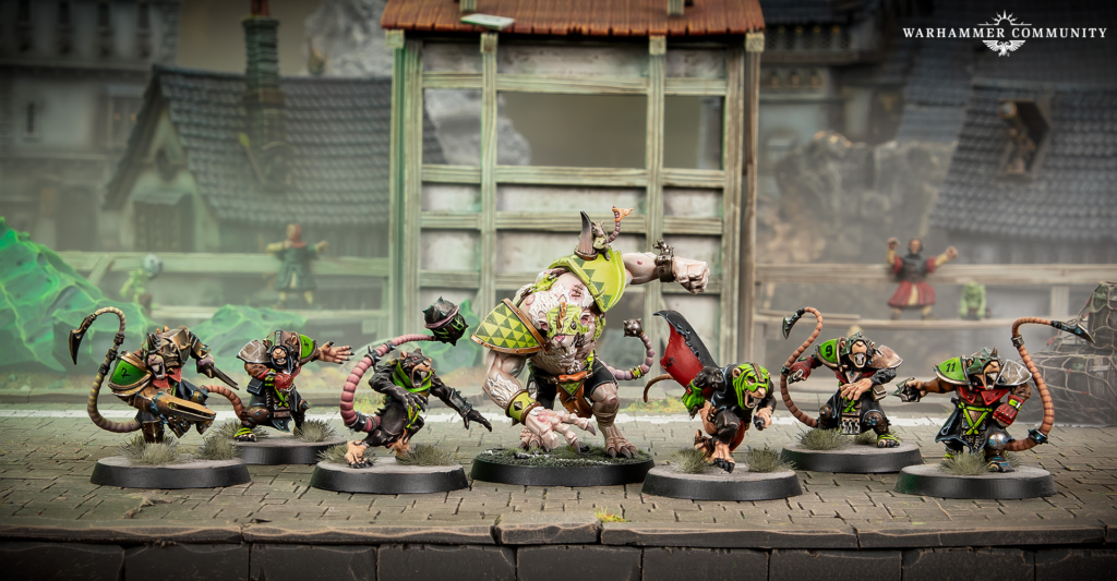 Tabletop miniature battle scene with a large armored ogre center stage surrounded by smaller rat like warriors on bases in a ruined urban setting