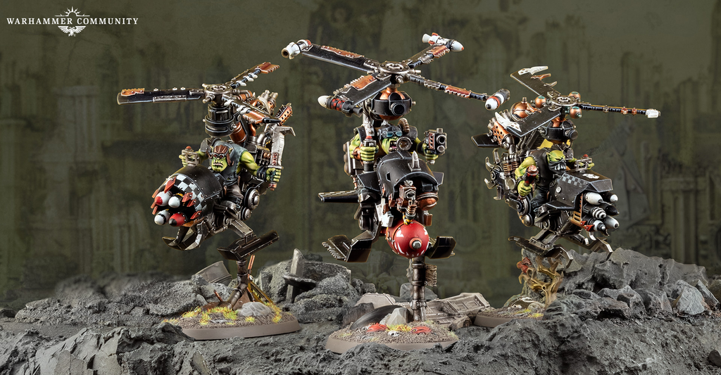Three Ork war machines with large rotor mounted weapons stand on a rocky diorama foregrounded by rubble and a muted backdrop I
