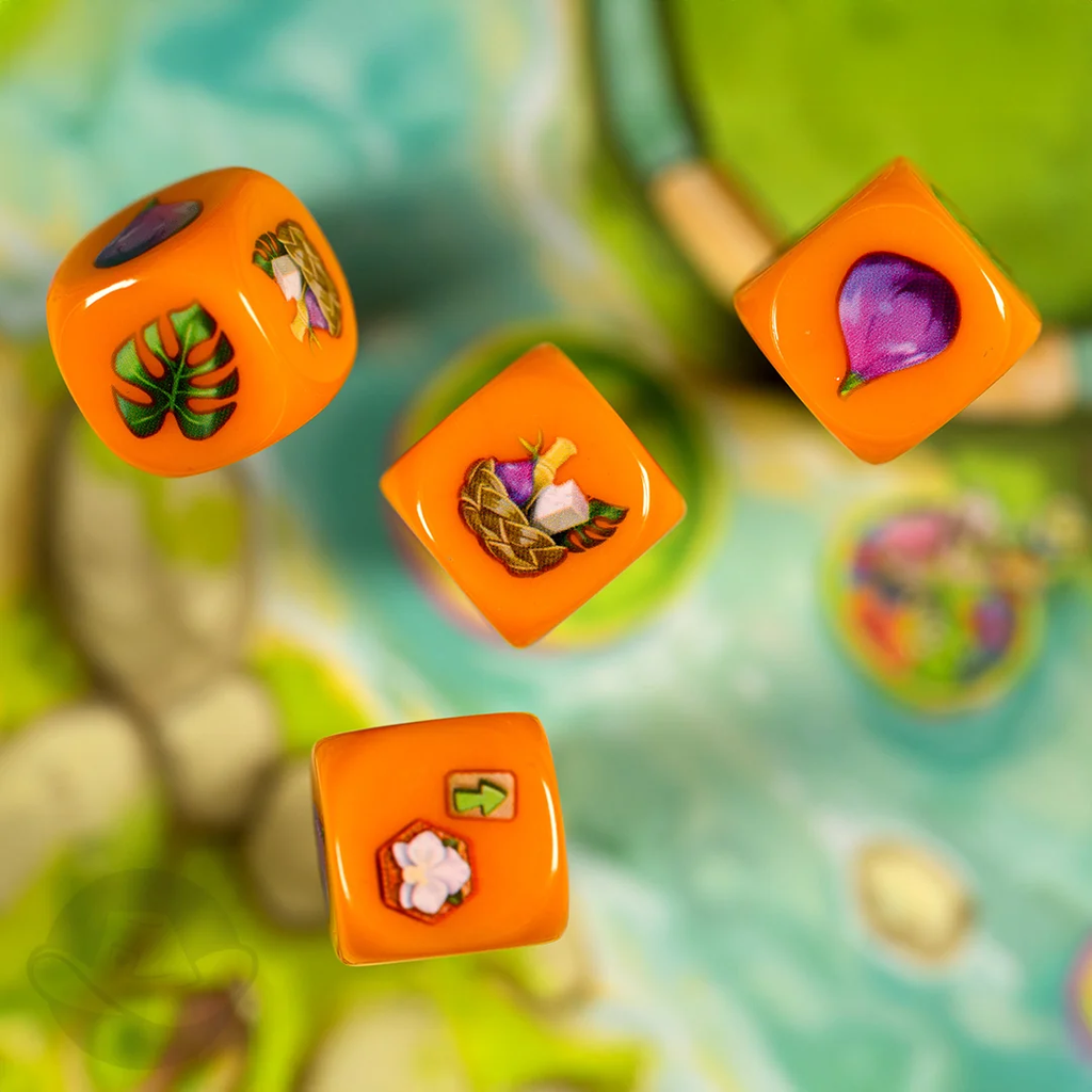 Bright orange dice with tropical themed stickers leaves fruit flowers arranged in a playful overhead shot Emerland review