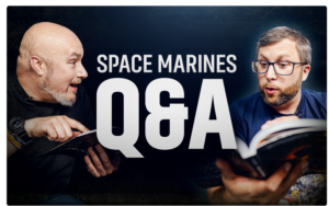 Two men reading a book together with a large QA graphic and Space Marines text in the background suggesting a discussion or live QA session