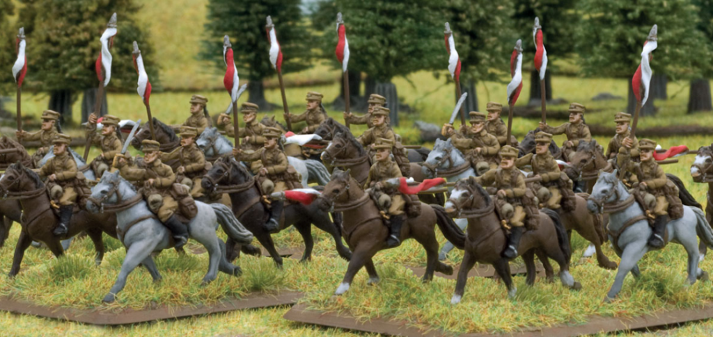 Group of miniature cavalry soldiers on horseback charging across a grassy battlefield diorama with red and white pennants