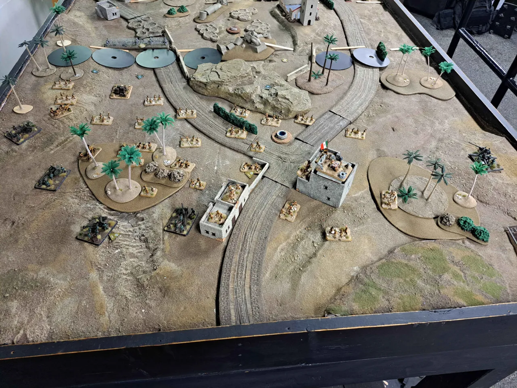 image Frontline Gaming Tabletop wargame battlefield with miniature soldiers palm trees and a curved train track layout on a sand toned table