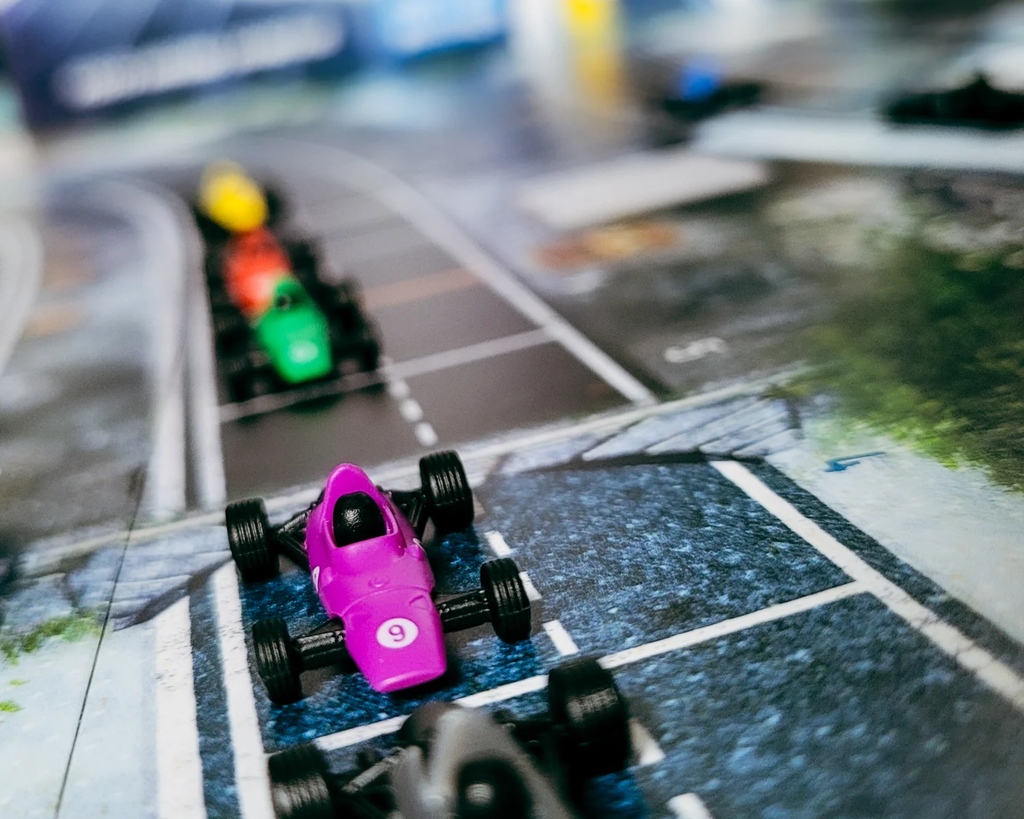 image Frontline Gaming Pink toy race car in the foreground on a blue city style race track with other cars blurred in the background appearing to race forward