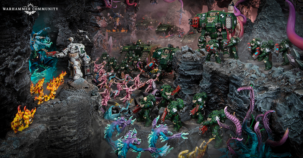 image Frontline Gaming Warhammer diorama green Space Marines clash with pink Tyranids amid tanks in a rocky lava lit cavern with a Warhammer Community logo in the corner