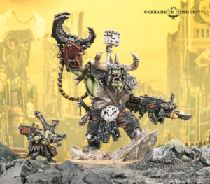 Green orc Warboss model in armor raises a large spiked hammer while holding a gun standing on a rocky battlefield