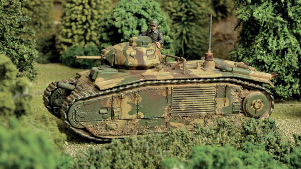 Camouflaged military tank model with a miniature soldier on top in a dense forest scene