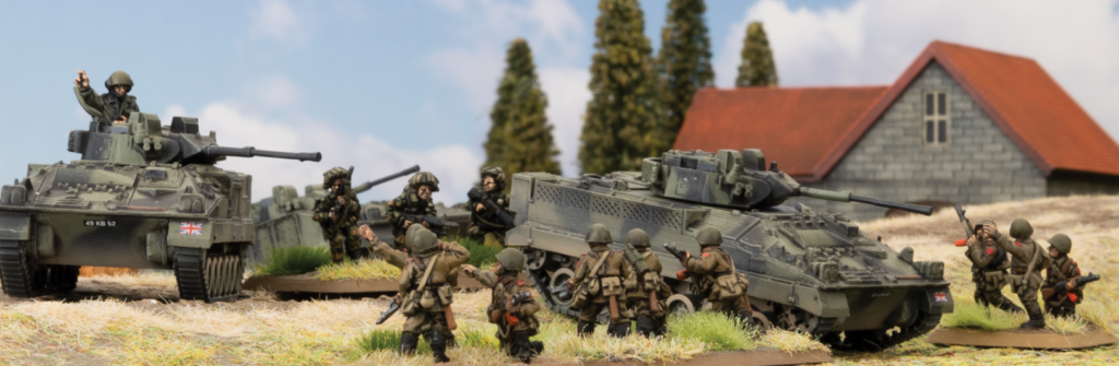 Scale model diorama of WWII battle two armored vehicles and groups of soldiers in a rural field with a barn in the background informative