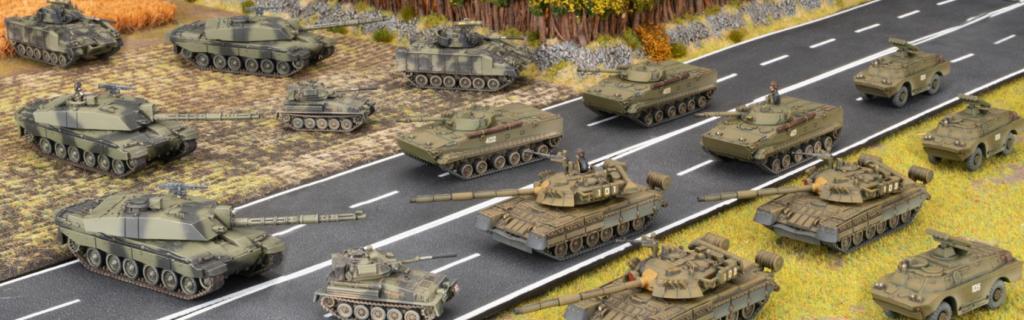Multiple armored tanks on a paved highway with additional tanks and vehicles off the road in a battlefield setting forming a convoy