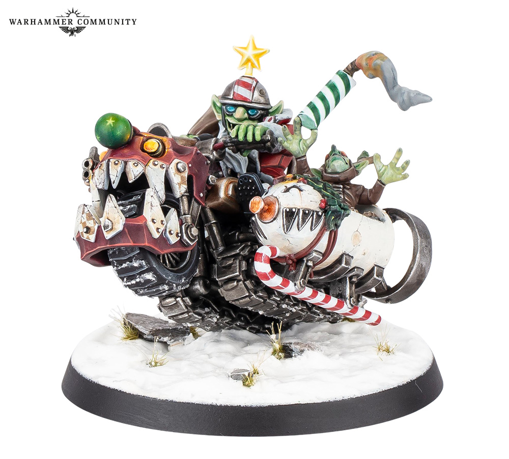 image Frontline Gaming Orc riders on a weaponized spiked vehicle racing across a snow covered base with a star on top and a Warhammer Community logo nearby