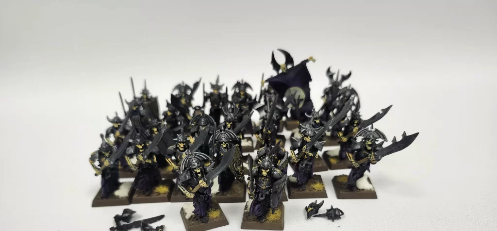rnimagepickerlibtemp915316af43734753804cfc31c8bf74d1 Frontline Gaming Group of dark armored skeleton miniatures with swords and shields arranged on square bases A card in front reads HOK 28 Grave Guard indicating the unit name and kit